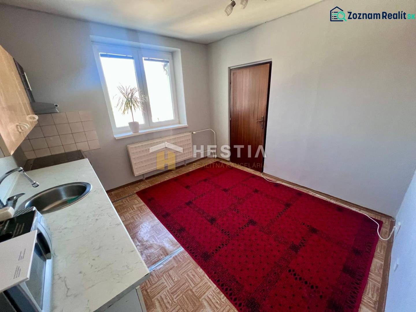 NOVINKA 3 izbový byt v Brezovej pod Bradlom s krásnym výhľadom - Kuchyňa 3-izbového bytu s kobercom, podlahou s dreveným dekorom a jednoduchým zariadením.