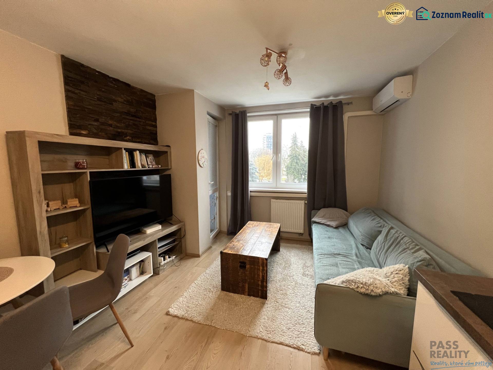 REZERVOVANÉ-PREDAJ 2 izbový byt s garážou v skvelej lokalite v Ružinov - Obývacia izba s podlahou s dreveným dekorom, pohovkou a televízorom v 2-izbovom byte.