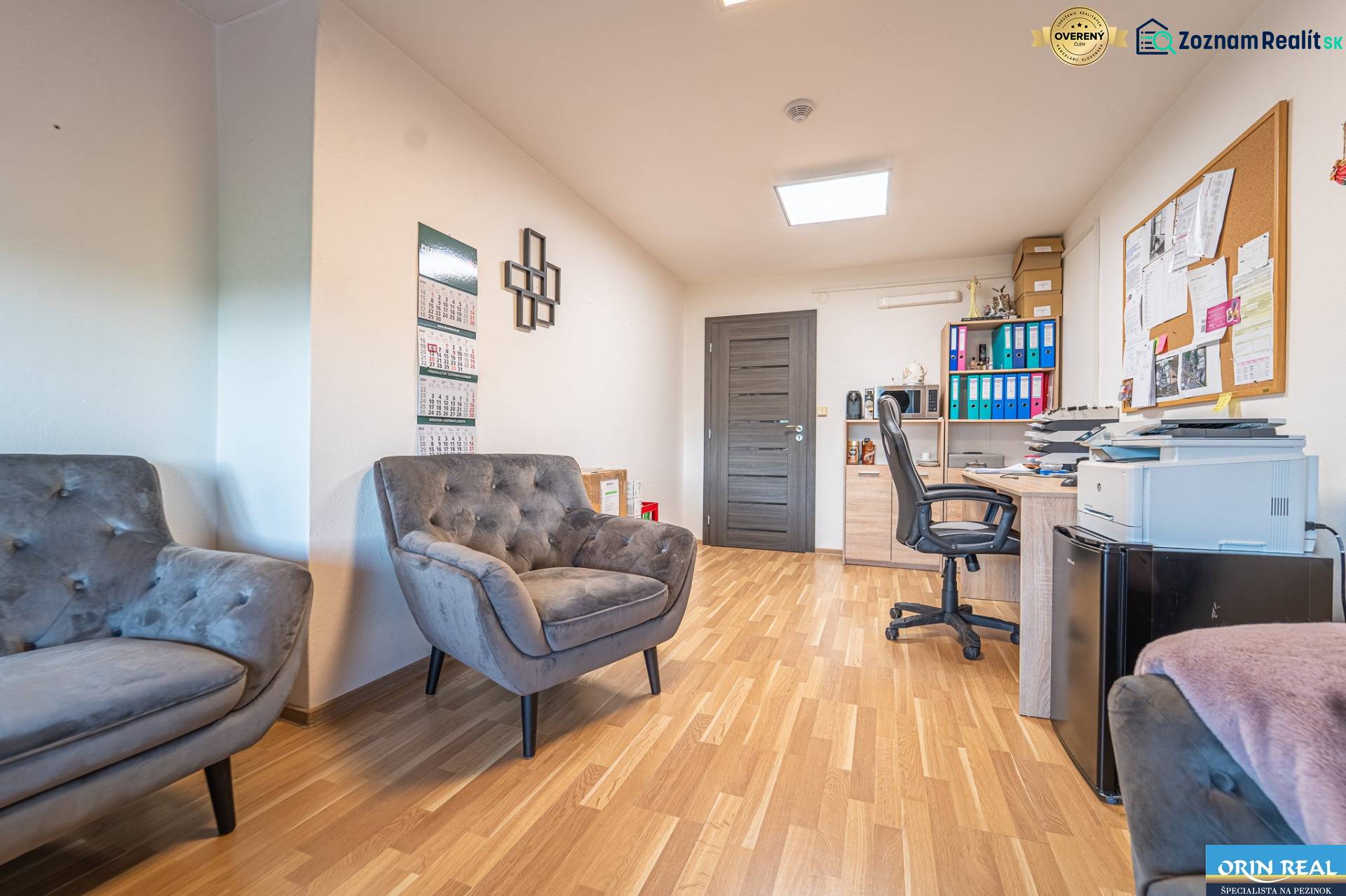 MODERNÝ KANCELÁRSKY PRIESTOR NA PRENÁJOM - Interiér kancelárie s podlahou s dreveným dekorom, pohodlnými kreslami a pracovným stolom.