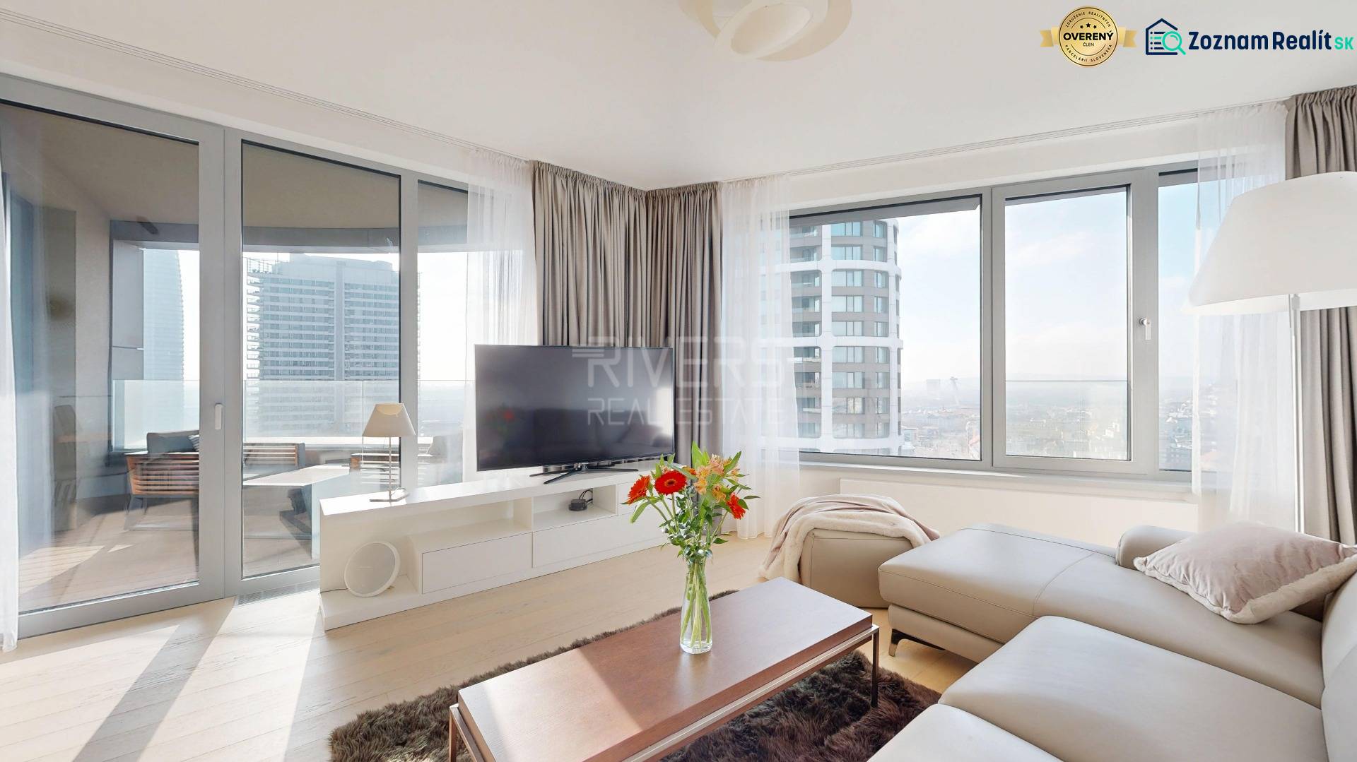 Elegantný byt na mieru s panorámou hradu  - Obývacia izba v 3-izbovom byte so sedačkou, televíziou a podlahou s dreveným dekorom.