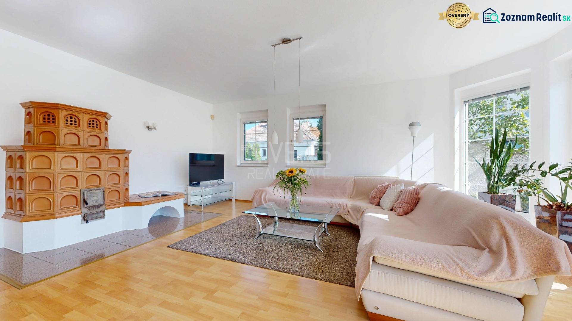 RIVERS - Veľkorysý rodinný dom po rekonštrukcii  - Obývacia izba v rodinnom dome s kachľovou pecou, rohovou sedačkou a podlahou s dreveným dekorom.