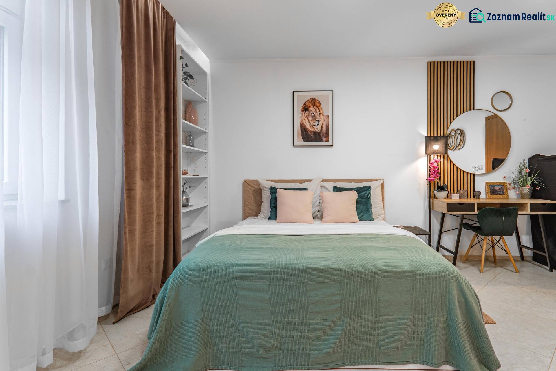 I Luxusný byt v historickom centre Bratislavy - Spálňa s posteľou, zelenou prikrývkou, pracovným stolom a dekoratívnymi prvkami v 2-izbovom byte.