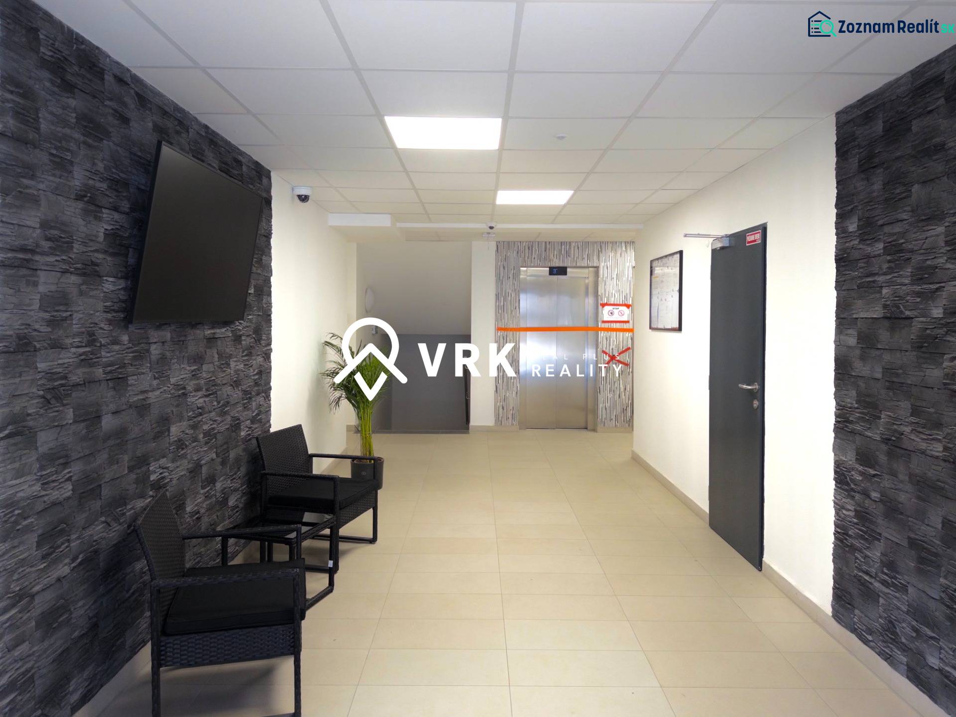 3-izbový byt s garážovým státím – Košice Západ, ul. Topoľčianska - Predsieň v 3-izbovom byte s TV na stene a výťahom v pozadí.