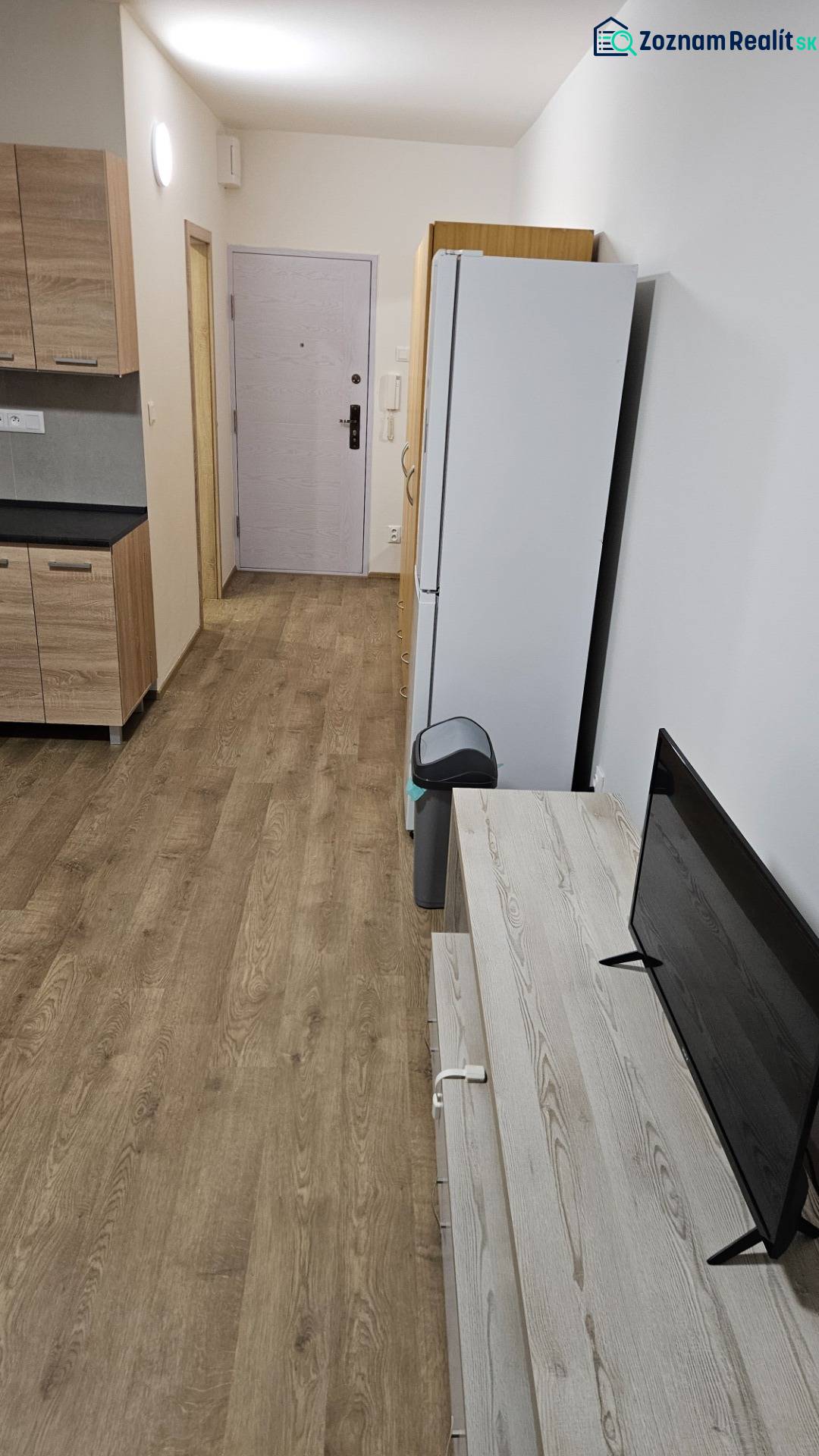Prenájom garsónka Dubnica nad Váhom  - Garsónka s podlahou s dreveným dekorom, kuchynskou linkou, chladničkou a televízorom.