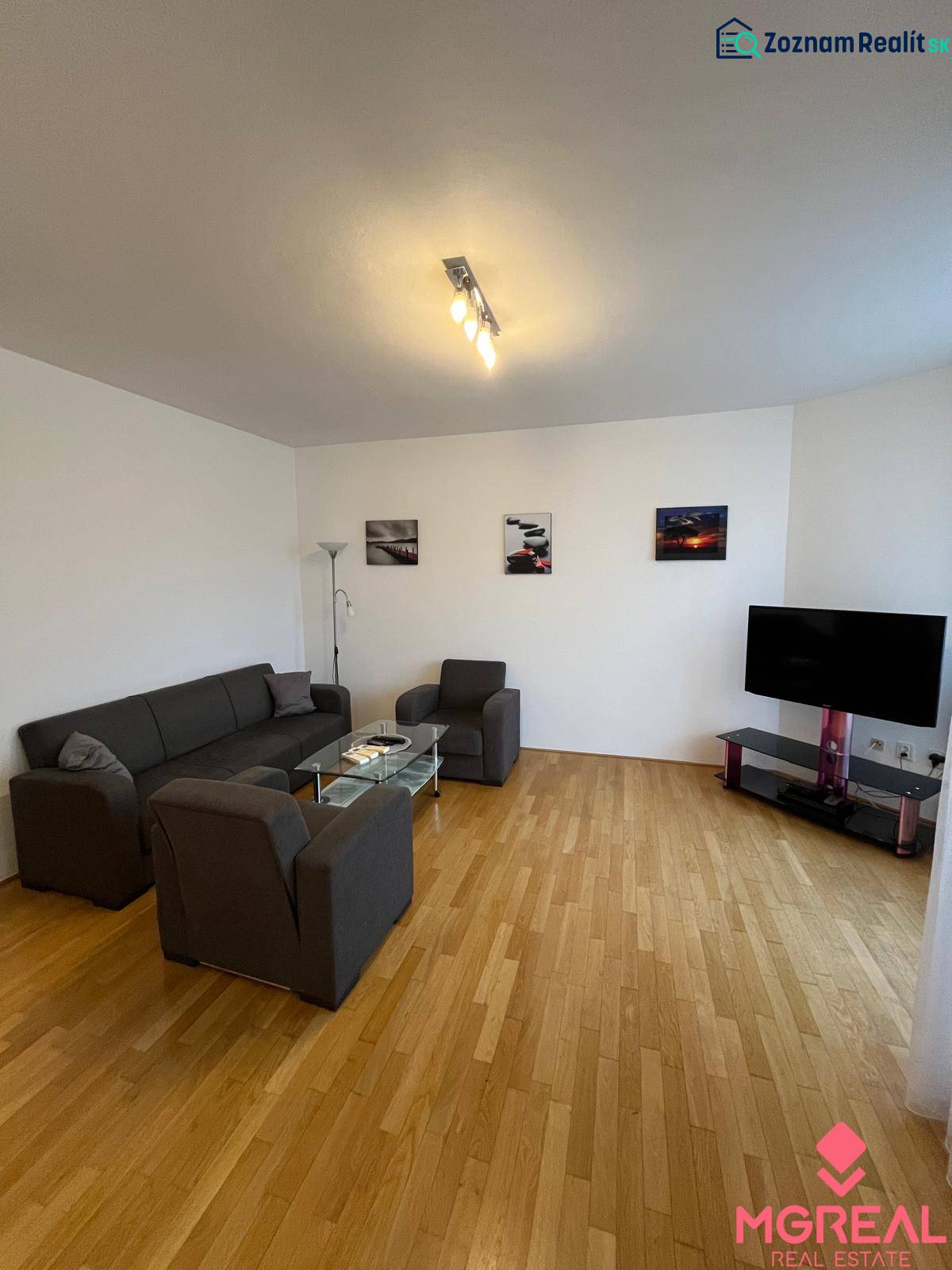 3i byt za cenu 2i bytu, Staré Mesto - Obývacia izba v 3-izbovom byte s podlahou s dreveným dekorom, sedačkou a televízorom.