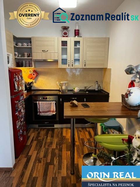 ÚTULNÝ 2 IZBOVÝ BYT - SILVANIUM  - Kuchyňa v 2-izbovom byte s drevenou podlahou, červenou chladničkou a barovým pultom.