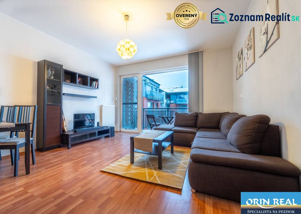 SVETLÝ ZARIADENÝ 2-IZBOVÝ BYT S BALKÓNOM - LA VITA  - Obývacia izba v 2-izbovom byte s podlahou s dreveným dekorom a sedacou súpravou.