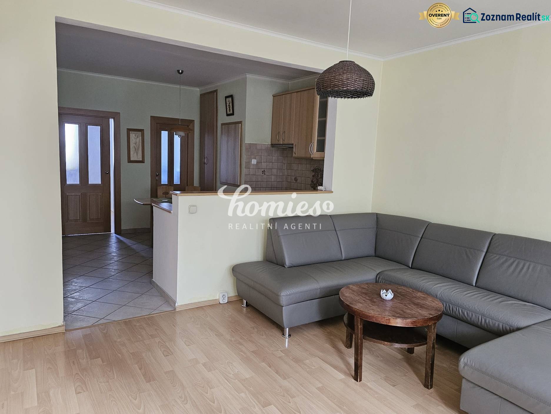 PRENÁJOM 3 izbový zariadený byt,  Nitra - Diely - Obývacia izba s rohovou sedačkou a podlahou s dreveným dekorom v 3-izbovom byte.