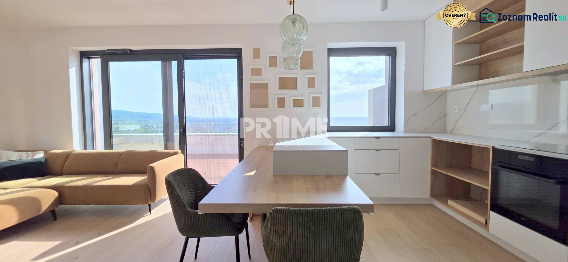 LUXUSNÝ 3i byt,PARKING,CHLADENIE,TERASA,Grand Koliba, Frankovská ulica - Svetlá obývacia izba s kuchyňou v 3-izbovom byte s veľkými oknami a hnedou sedačkou.