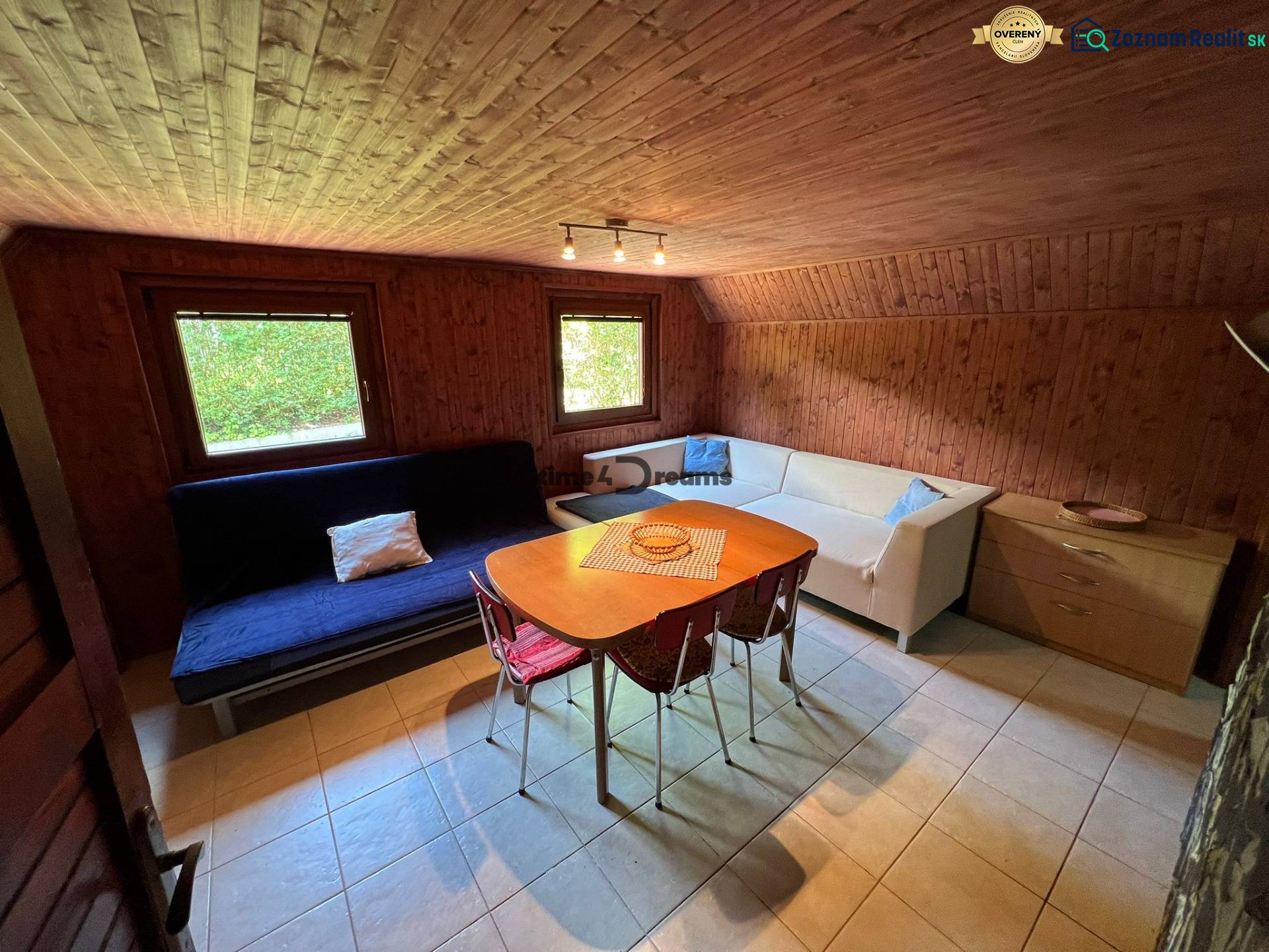 NA PREDAJ Chata na Duchonke- Prašice - Izba v chate s dreveným obkladom, sedačkou a stolom s jedálenskými stoličkami.