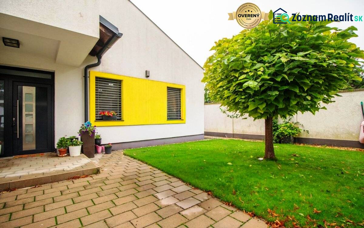 Priestranný 5-izbový rodinný dom s pohodlným dojazdom do Bratislavy  - Rodinný dom so žltým obkladom, dlažbou a zeleným trávnikom v Nitre.