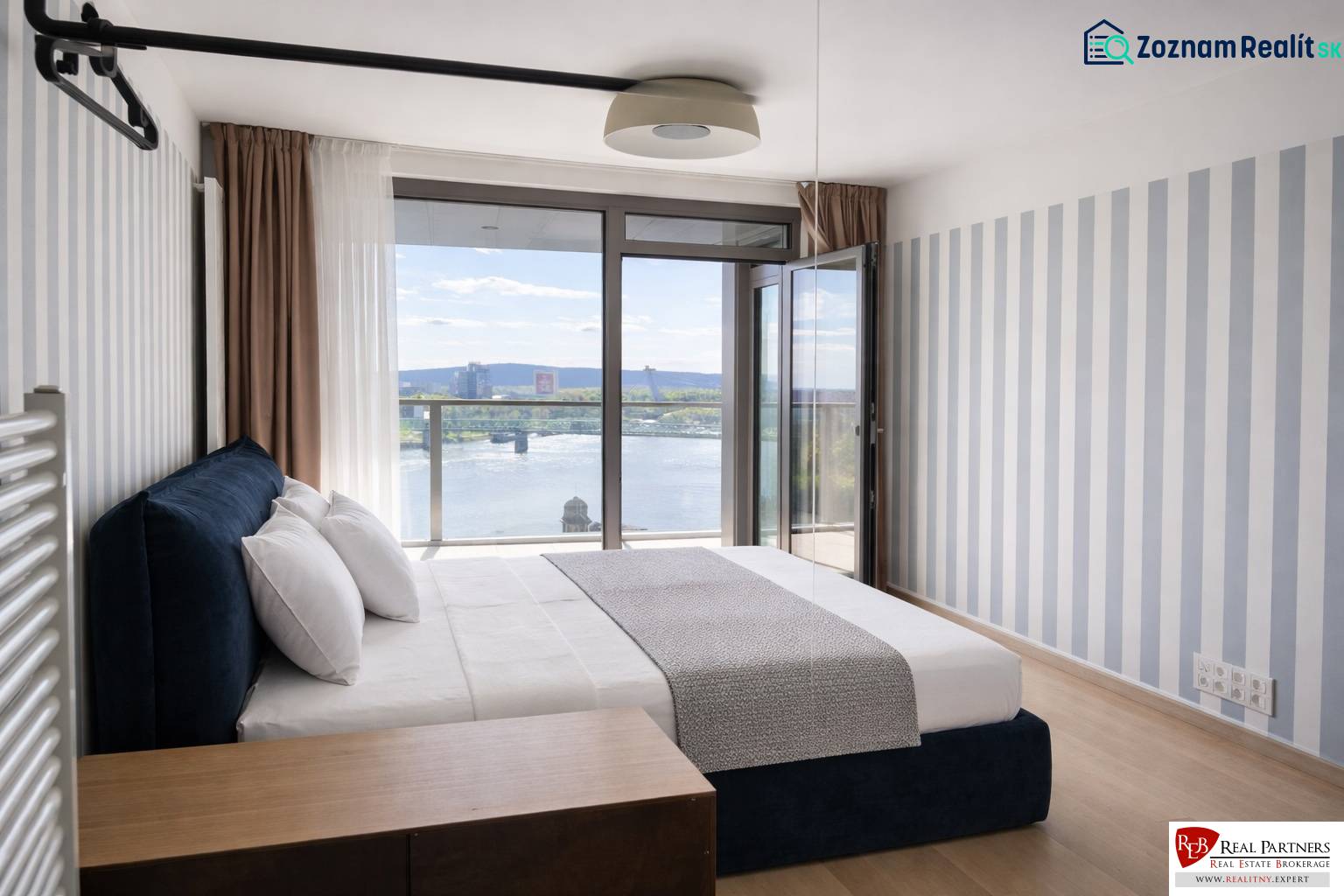 Prenájom 2-izbový byt s loggiou,55m2, EUROVEA TOWER - Spálňa v 2-izbovom byte s výhľadom na rieku, podlaha s dreveným dekorom.