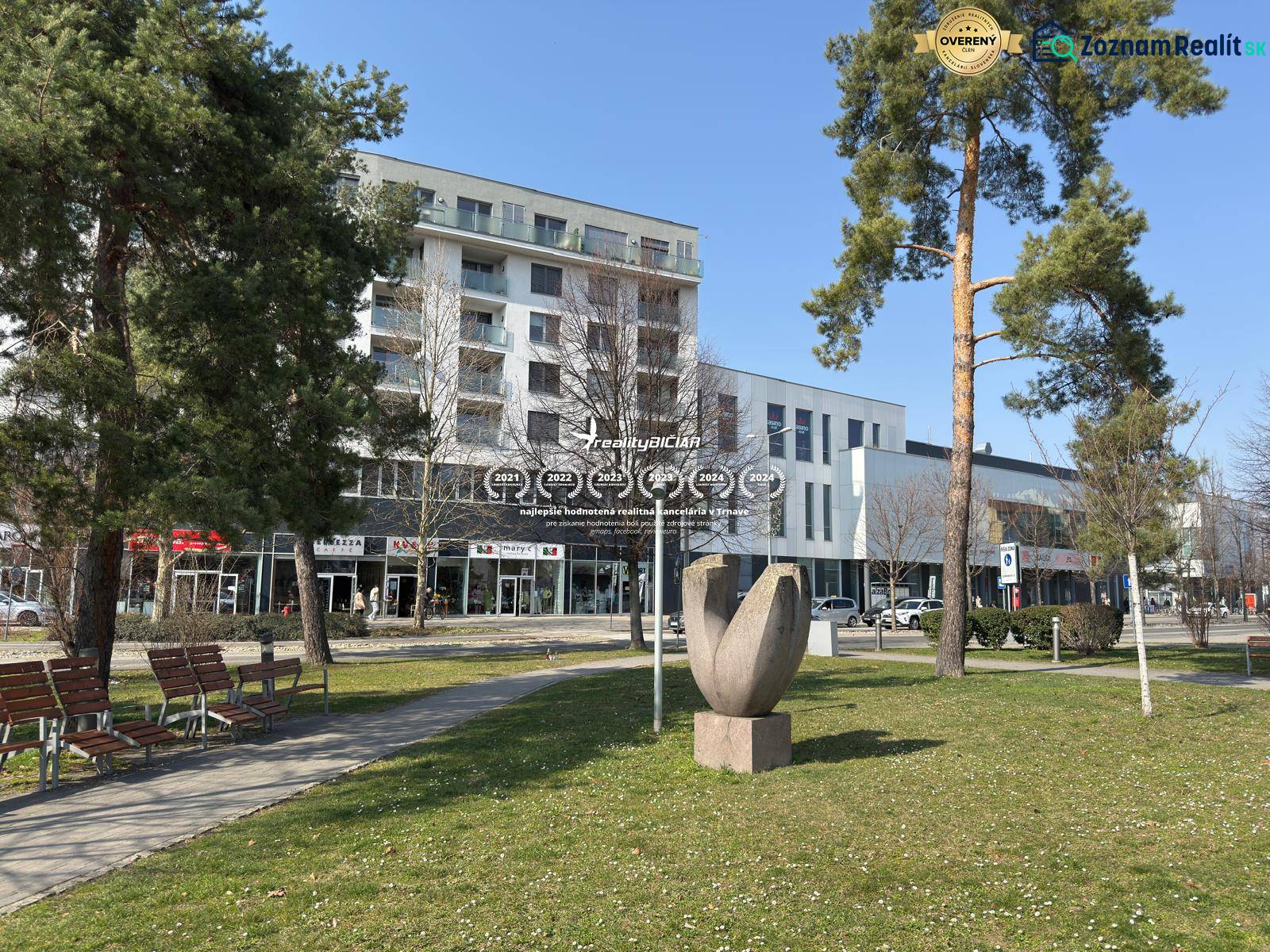 EXKLUZÍVNE: Celé podlažie v centre Piešťan s projektom apartmánov - Budova na nitrianskej 755 v Piešťanoch, obklopená zeleňou a lavičkami.