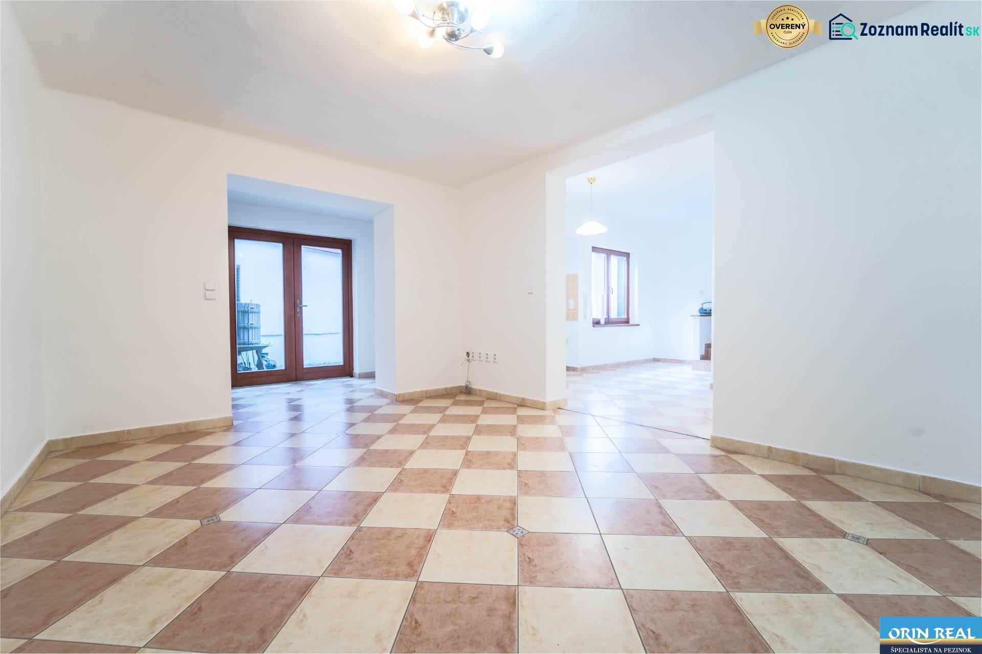 RD PO REKONŠTRUKCII spolu so STAVEBNÝM POZEMKOM na druhý dom - takmer  - Priestranná miestnosť v rodinnom dome s kachličkovou podlahou a drevenými dverami na terasu.