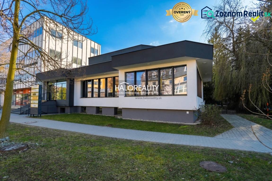 Predaj, polyfunkcia/obchodné priestory Považská Byst... - Exteriér obchodných priestorov v Považskej Bystrici s chodníkom a stromami.