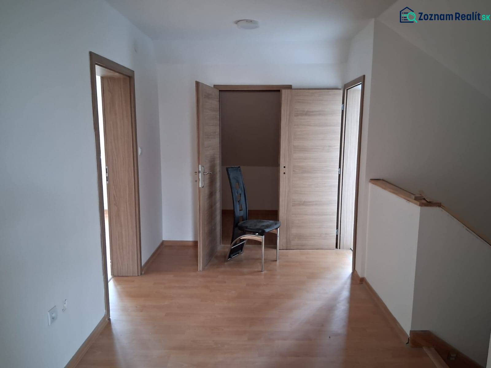 PREDAJ – 4-izbový rodinný dom v radovej zástavbe s garážou - Izba v rodinnom dome s podlahou s dreveným dekorom a tromi drevenými dverami.