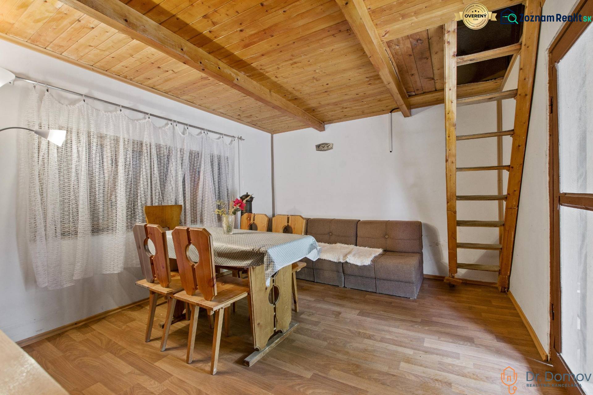 NA PREDAJ CHATA V REKREAČNEJ OBLASTI RUDAVA, OBEC MALÉ LEVÁRE - Interiér chaty s dreveným schodiskom, jedálenským stolom a podlahou s dreveným dekorom.