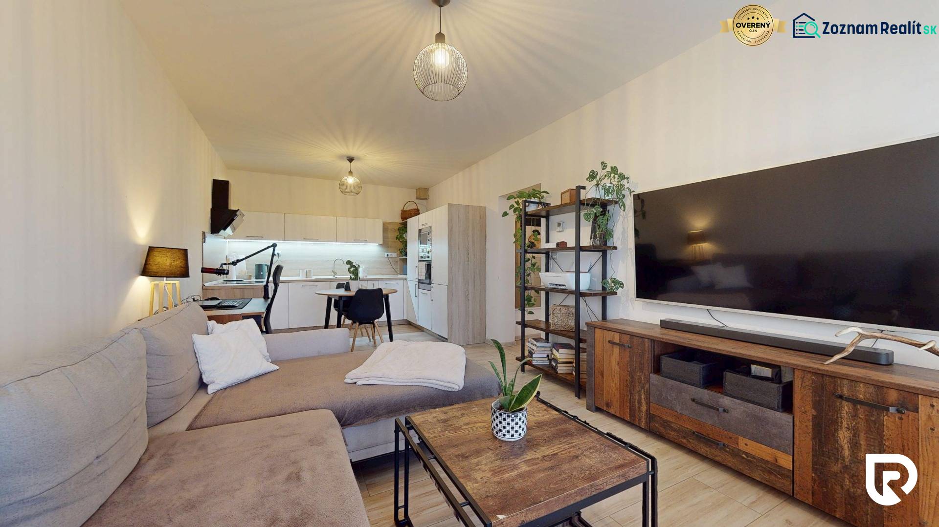 RADO I 2-izbový byt 49m² s terasou 71m² I Soblahov - Obývacia izba v 2-izbovom byte s pohovkou, televízorom a kuchynským kútom.