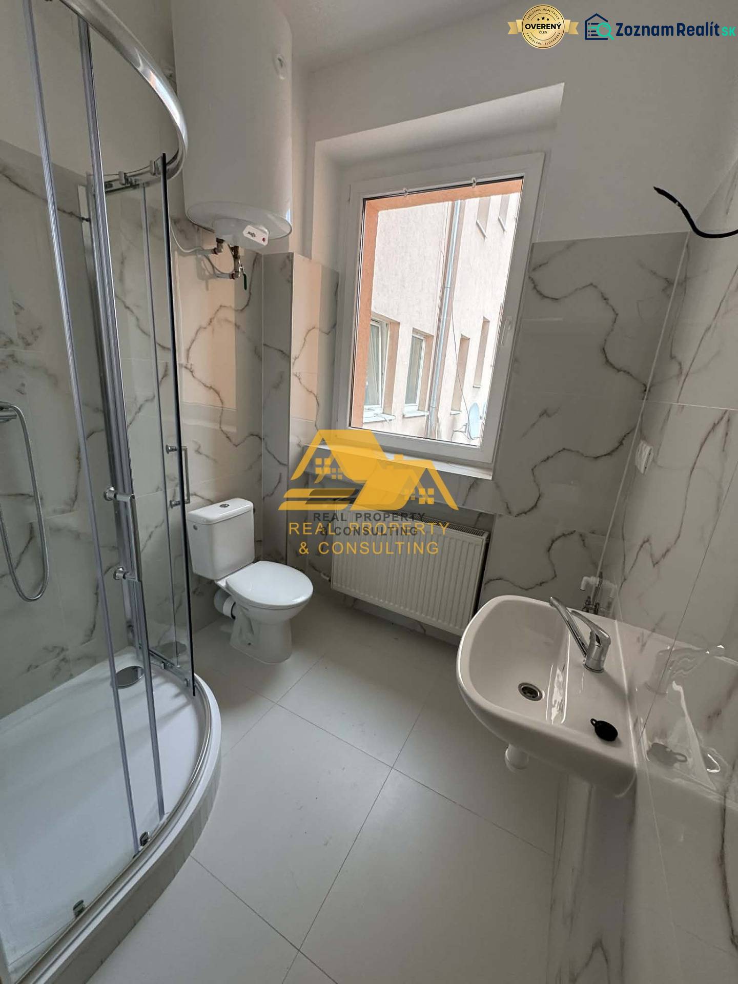 Prenajmem 1 izbový byt v Nových Zámkoch - Kúpeľňa v 1-izbovom byte s rohovým sprchovacím kútom a keramickými obkladmi.