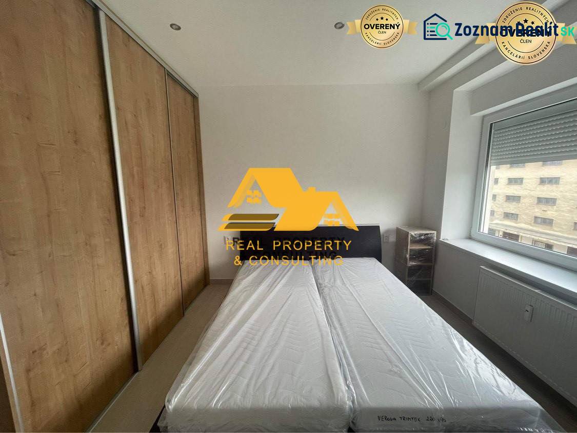 Prenajmem zariadený 3 izbový byt v Nových Zámkoch - Spálňa v 3-izbovom byte s posteľou, vstavanou skriňou a oknom s výhľadom.