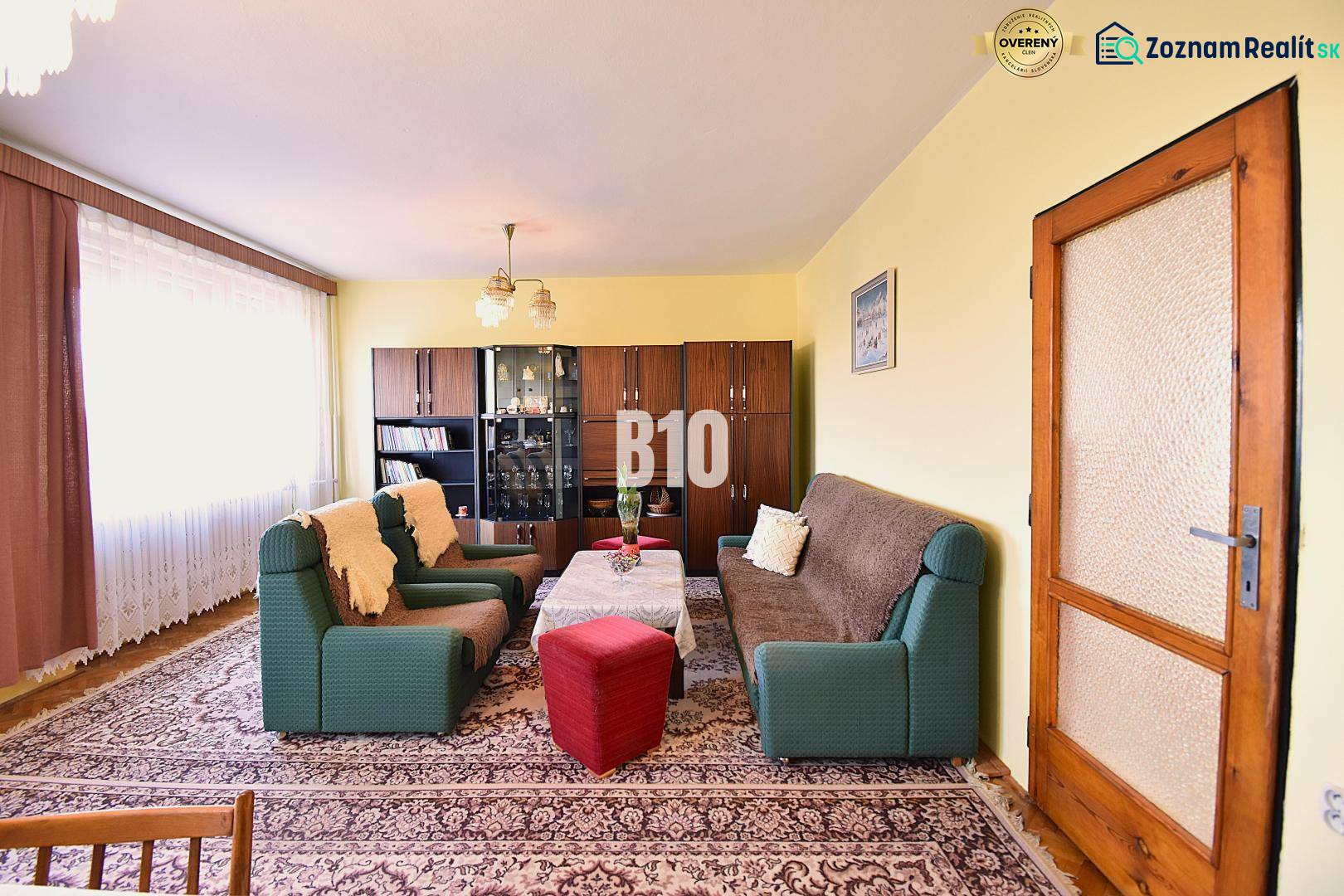 5 izbový  rodinný dom vo Varíne - Obývačka v rodinnom dome s pohovkami, kreslami, vitrínou a kobercom.