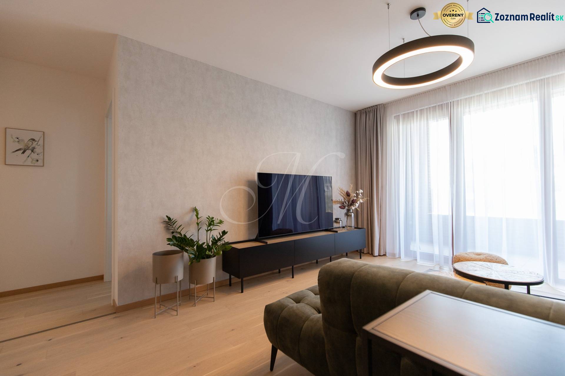 2-izbový byt s lodžiou v projekte Zwirn - Obývací priestor v 2-izbovom byte s podlahou s dreveným dekorom a televízorom.