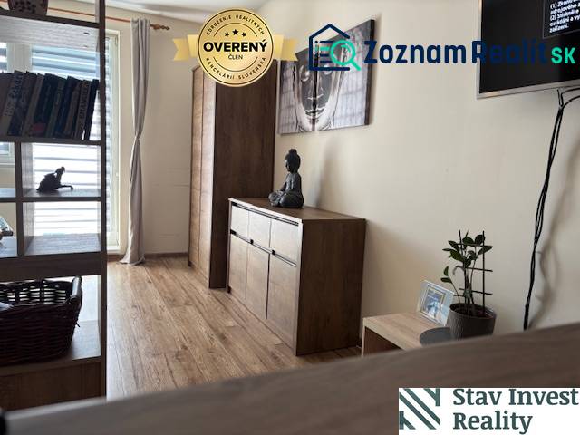 Exkluzívny investičný apartmán/byt  na predaj v srdci Donovál  - Interiér 1-izbového bytu s nábytkom z dreveným dekorom a umením na stene.