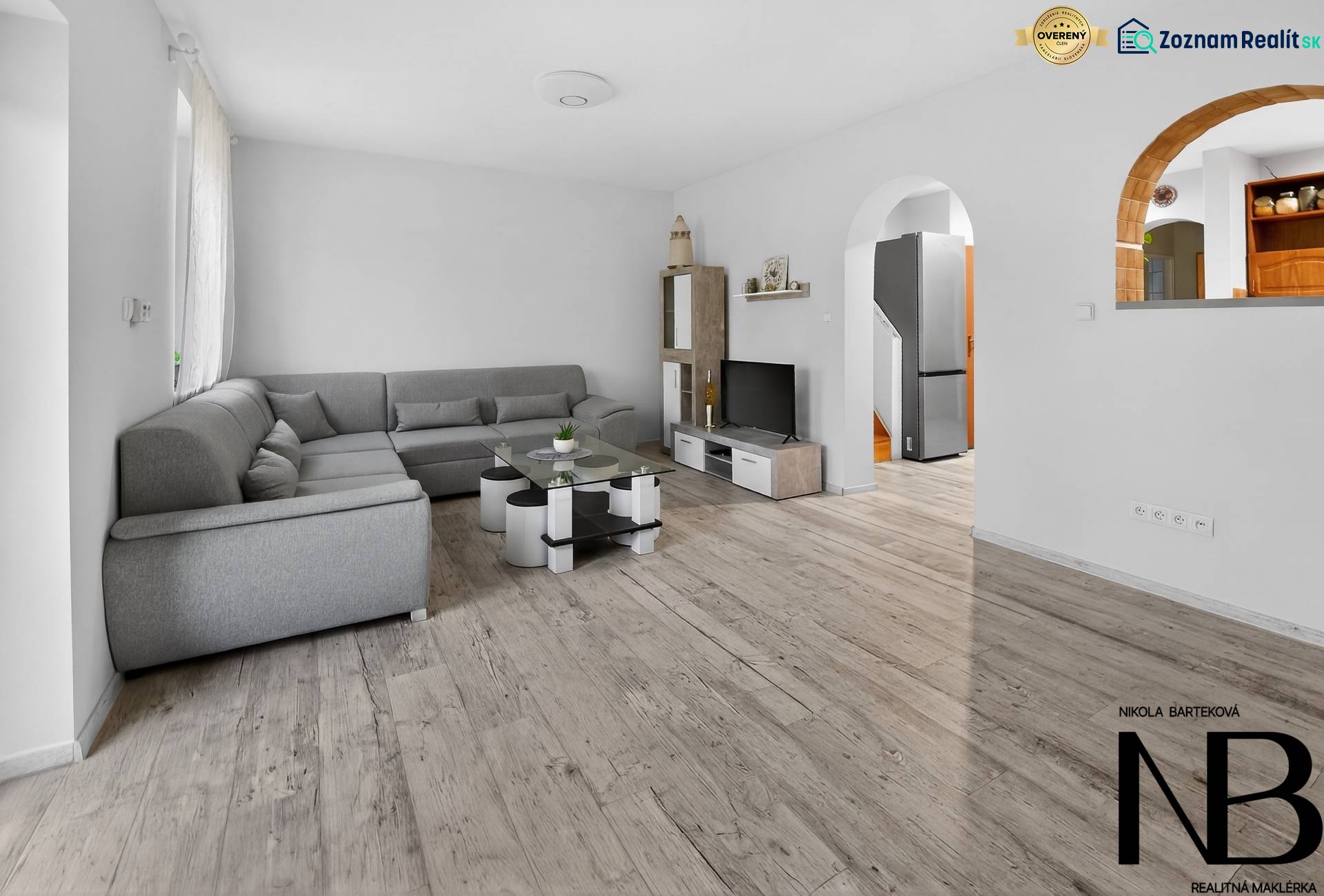 Rodinný dom s veľkým pozemkom a priestorom na podnikanie – T.Jastrabie - Obývacia izba v rodinnom dome s pohodlnou sivou sedačkou a podlahou s dreveným dekorom.