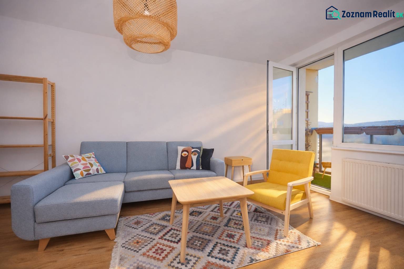NA PREDAJ-3-izbový byt s loggiou a výhľadom na centrum mesta, KE-JUH - Obývačka so sedačkou, žltým kreslom, koberec a podlaha s dreveným dekorom v 3-izbovom byte.