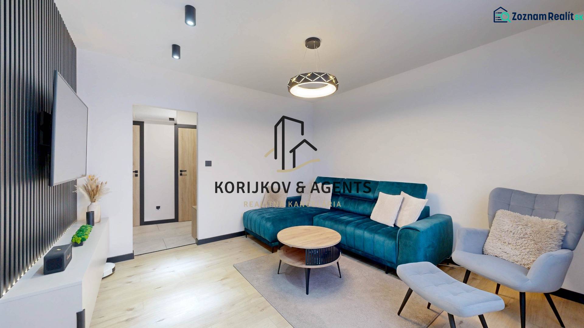 PREDAJ, 3 izbový dizajnový byt na Lidickom námestí, Košice - Furča - Obývačka v 3-izbovom byte s modrou sedačkou a podlahou s dreveným dekorom.
