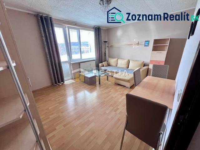 Prenájom 2‑izbového kompletne zariadeného bytu v Brezovej pod Bradlom - Obývacia izba 2-izbového bytu s podlahou s dreveným dekorom a svetlým nábytkom.