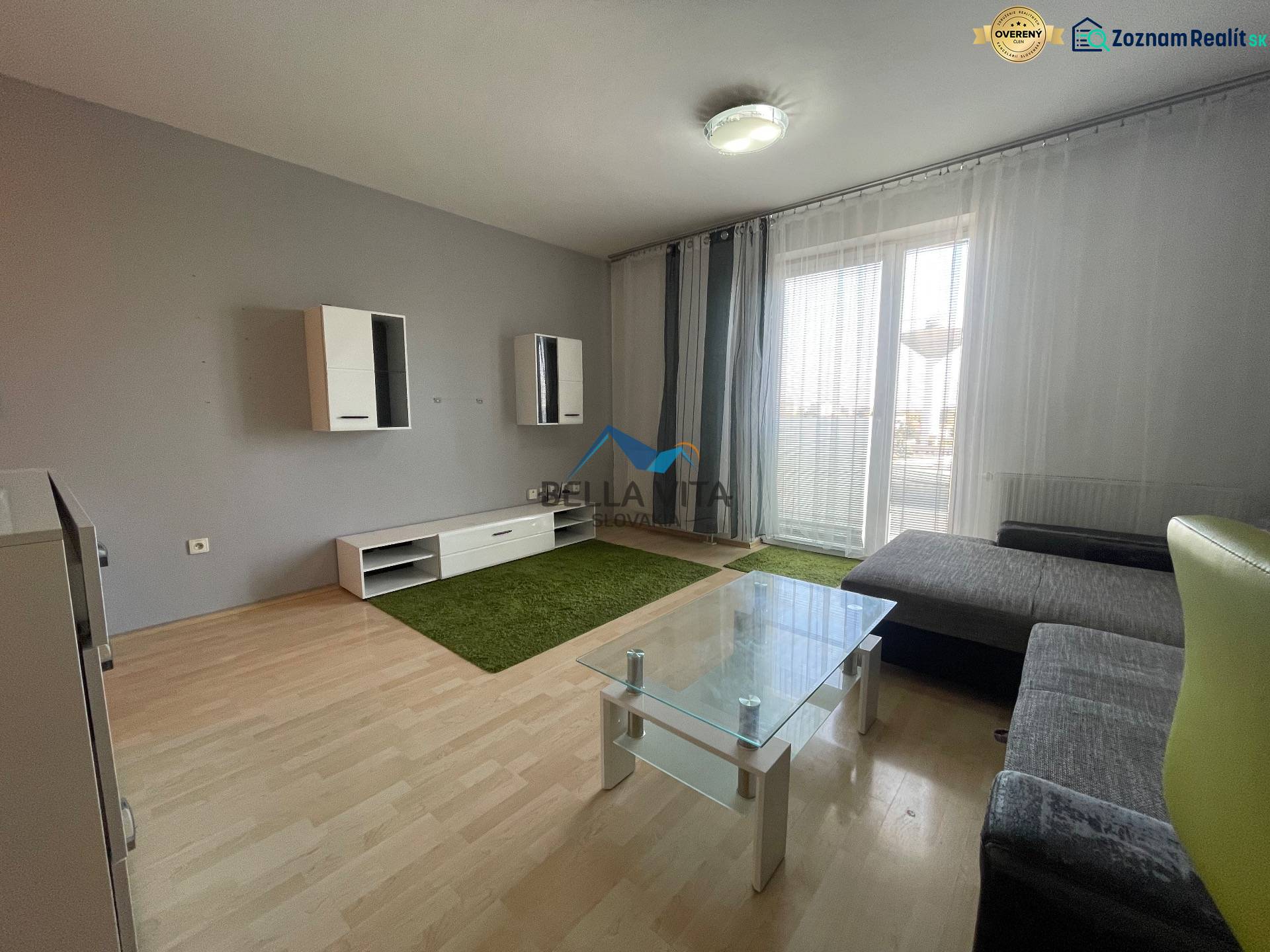 Prenájom 1 izbový byt v Galante, Hodská - Obývacia izba v 1-izbovom byte s podlahou s dreveným dekorom, pohovkou a sklom stolíkom.