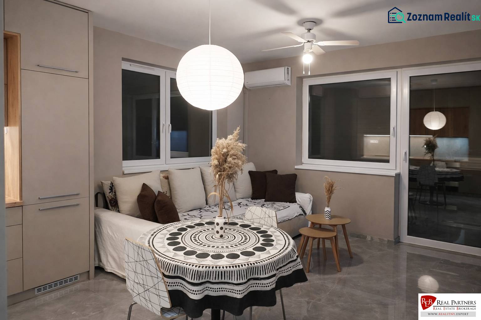 Predaj 2-izbový byt GREEN VILLAGE,44m2, loggia, Dunajská Lužná - Obývacia izba s pohovkou, okrúhlym stolom a ozdobným svietidlom v 2-izbovom byte.