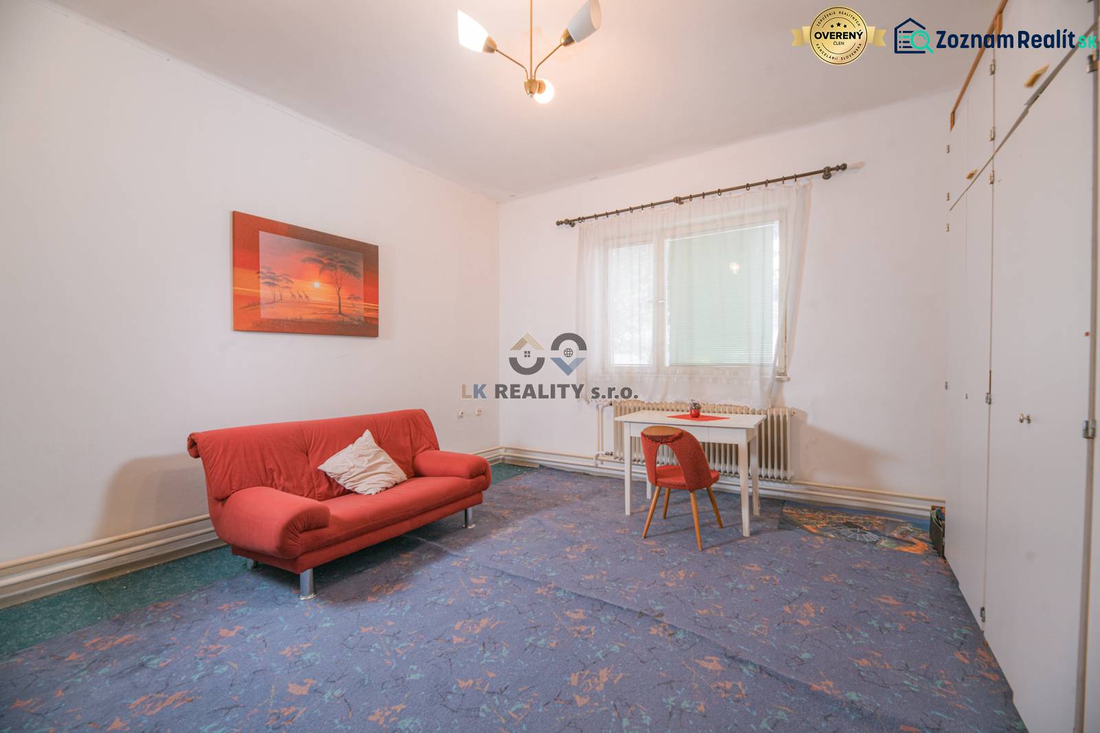 Na predaj rodinný dom Trnava, Zelenečská ulica, pozemok 1085 m2 - Obývacia izba v rodinnom dome s červenou pohovkou a stolom so stoličkou.