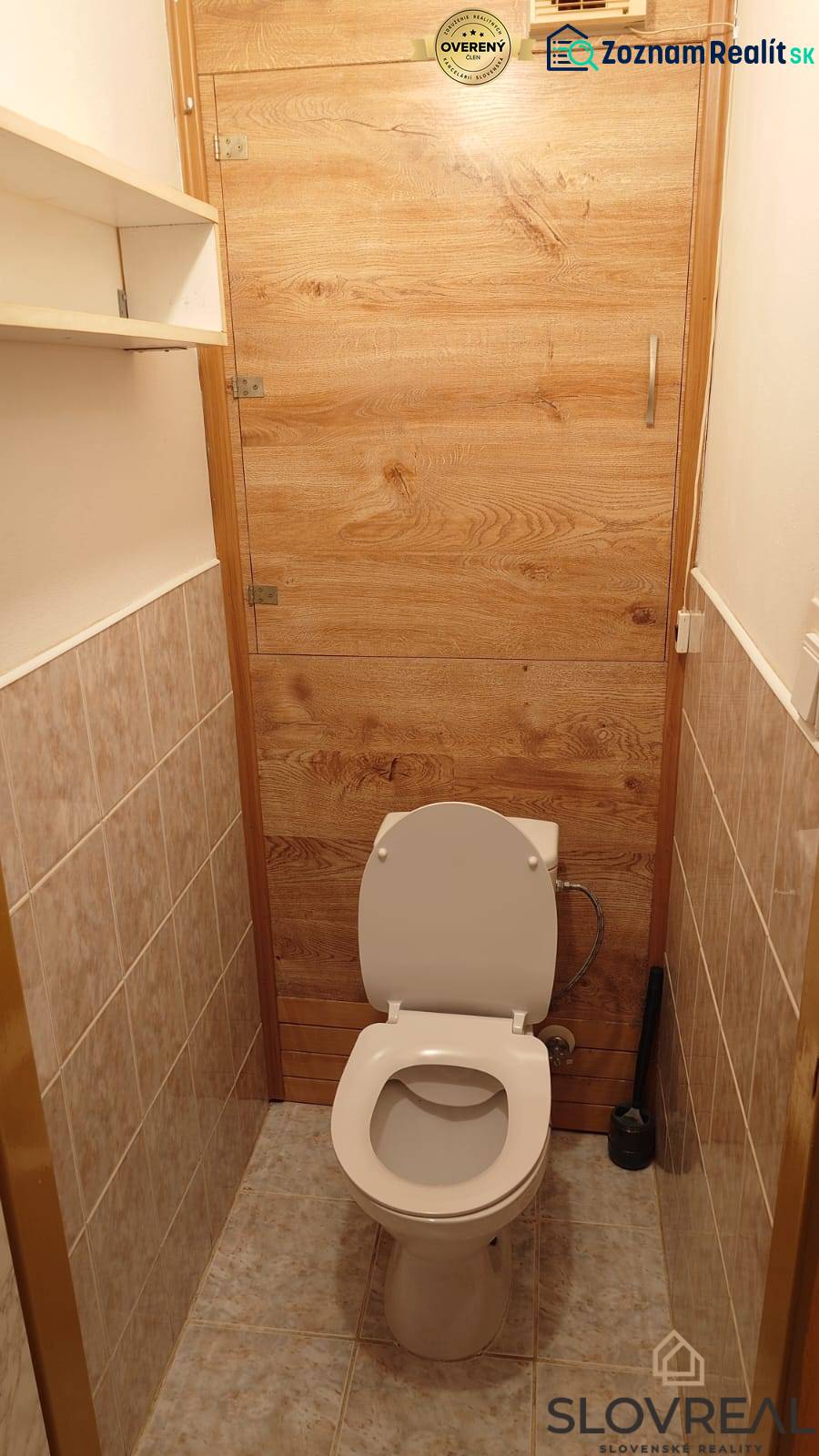 Na predaj 2i byt Levice - Toaleta so stenami obloženými dlažbou a dverami s dreveným dekorom v 2-izbovom byte.