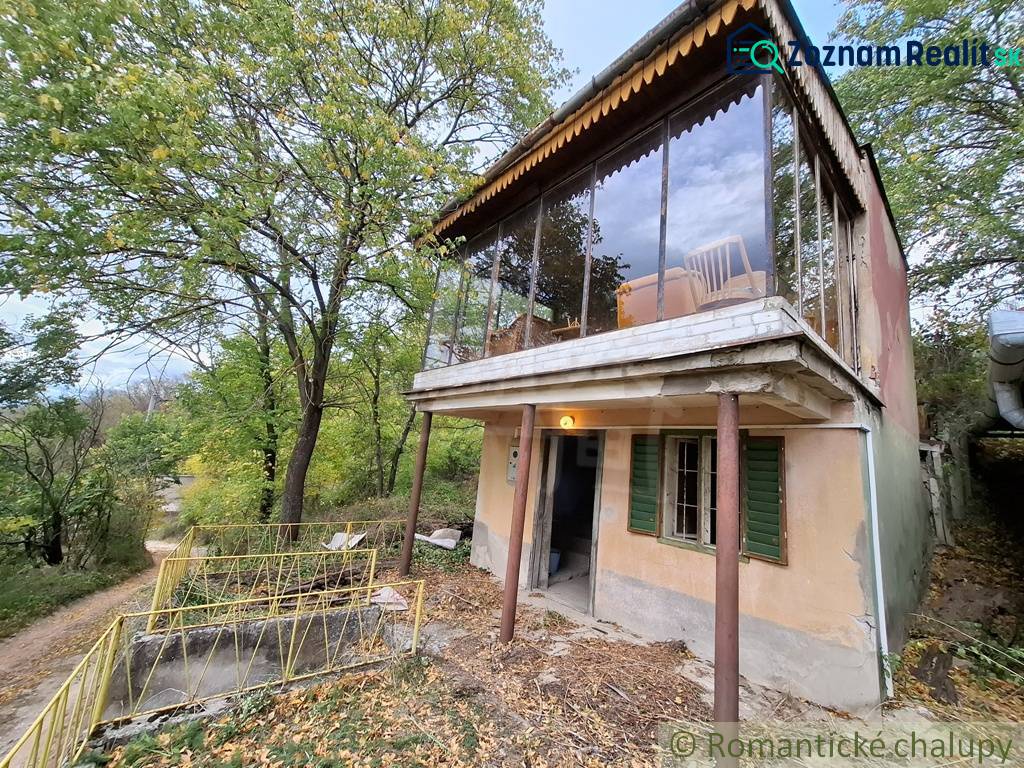 Pôvodná chata s panorámou nad korunami stromov blízko Hrona v rekreačn - Chata v Kameníne obklopená zeleňou, so sklenenou terasou a príjazdovou cestou.