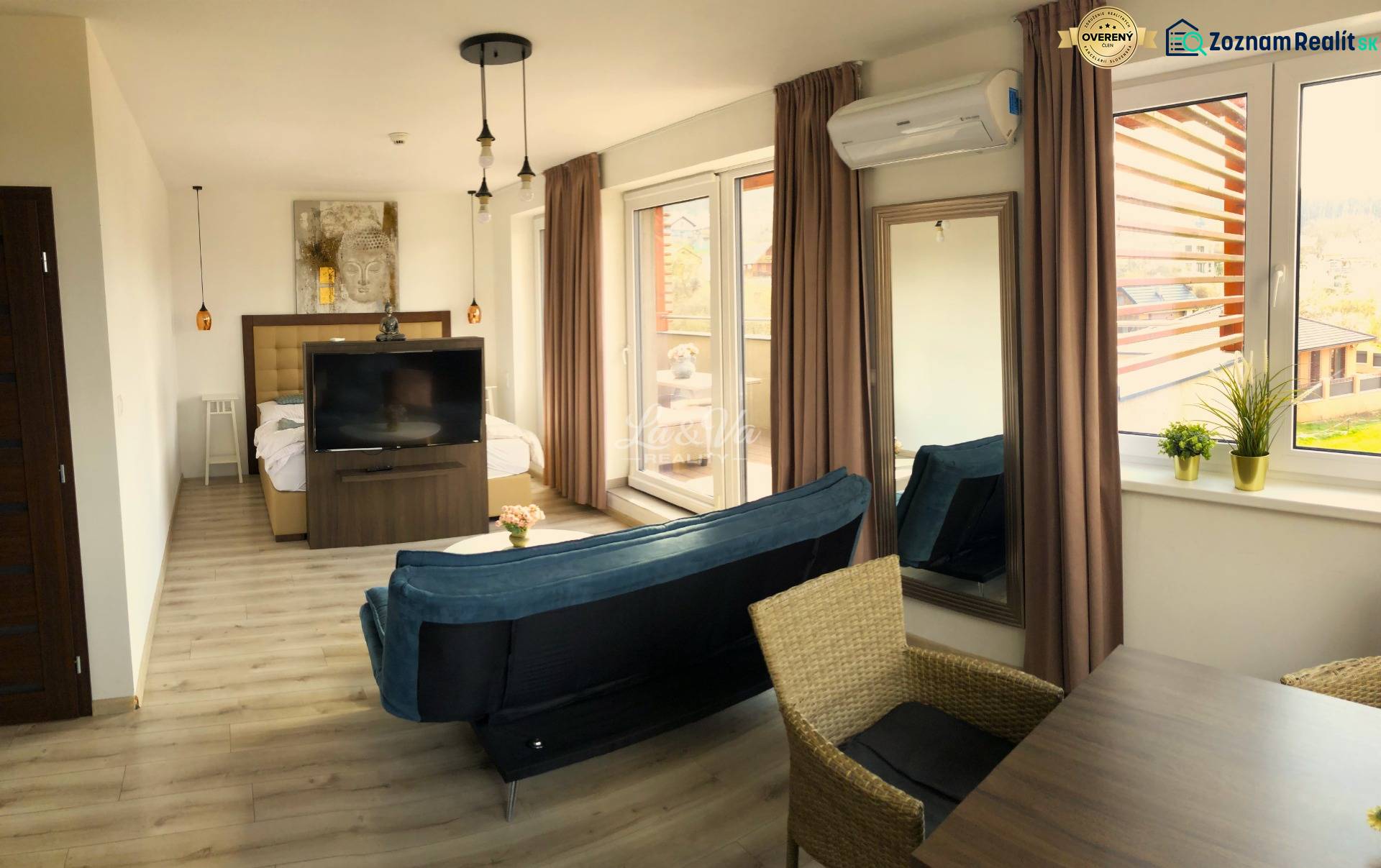 Na predaj štyri apartmány na jednom poschodí Podhájská - Svetlý 2-izbový byt s podlahou s dreveným dekorom, pohovkou a veľkými oknami.