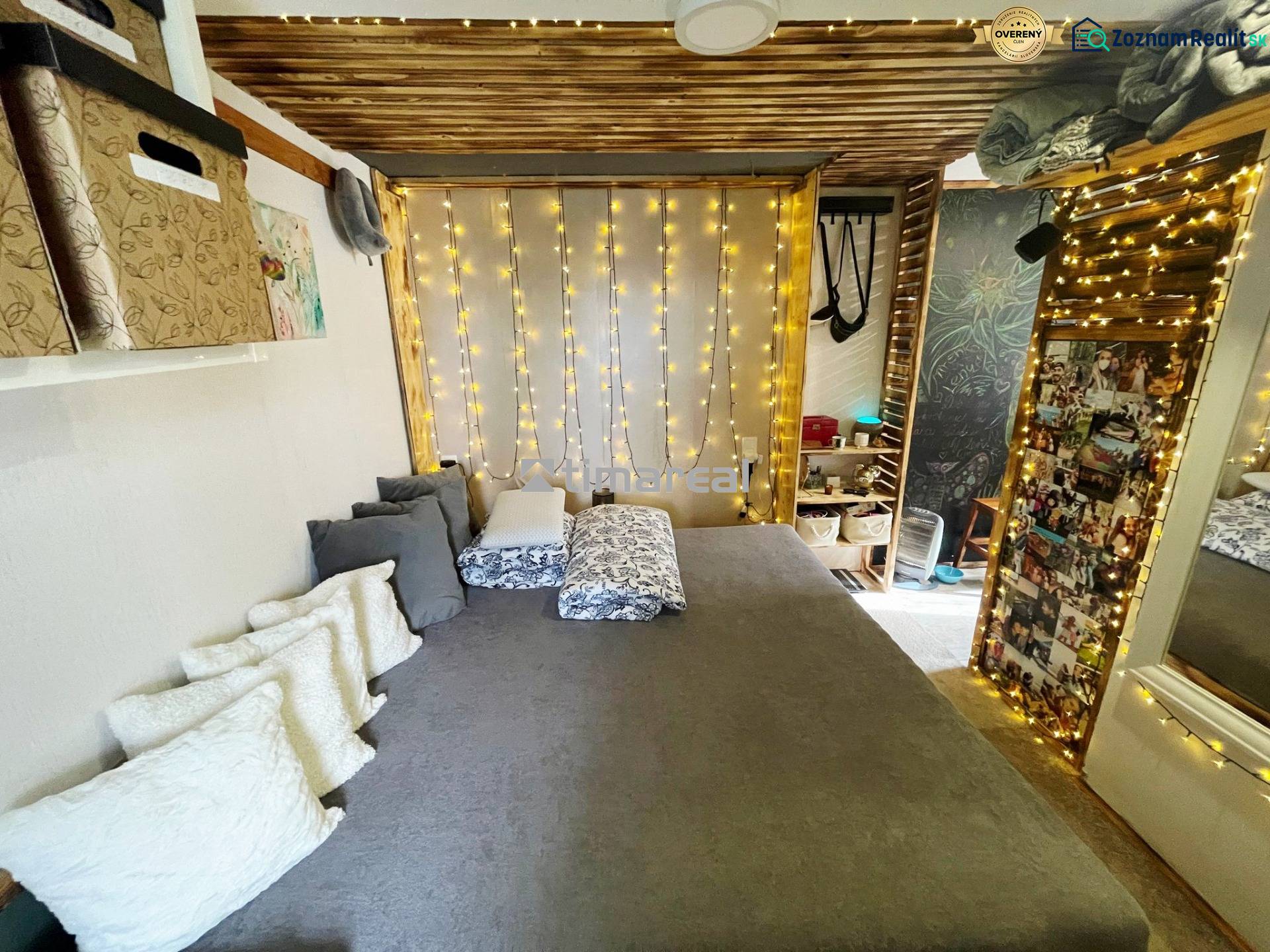 Bývanie v prírode, na dosah mesta, murov. chatka s celoročným využitím - Interiér rodinného domu s posteľou, vankúšmi a svetelnou dekoráciou.