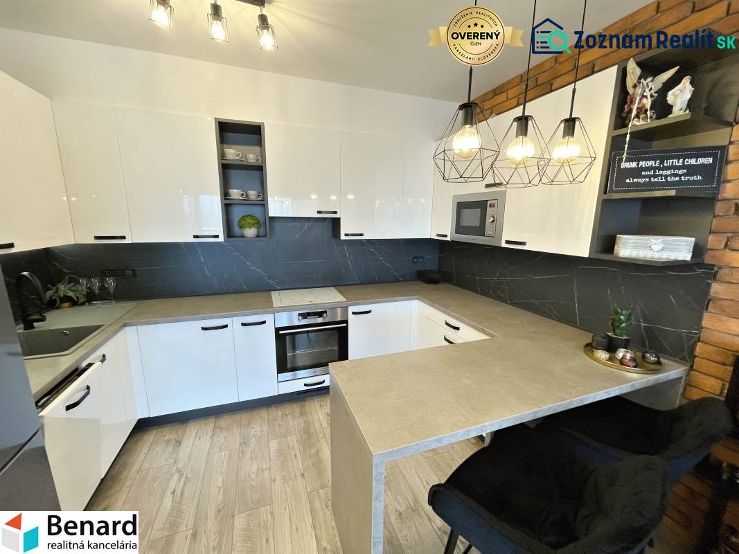 KOŠICE-2 IZBOVÝ BYT,NOVOSTAVBA,KOMPLET ZARIADENÝ,VL.PARK. MIESTO - Kuchyňa v 2-izbovom byte s bielymi skrinkami a podlahou s dreveným dekorom.