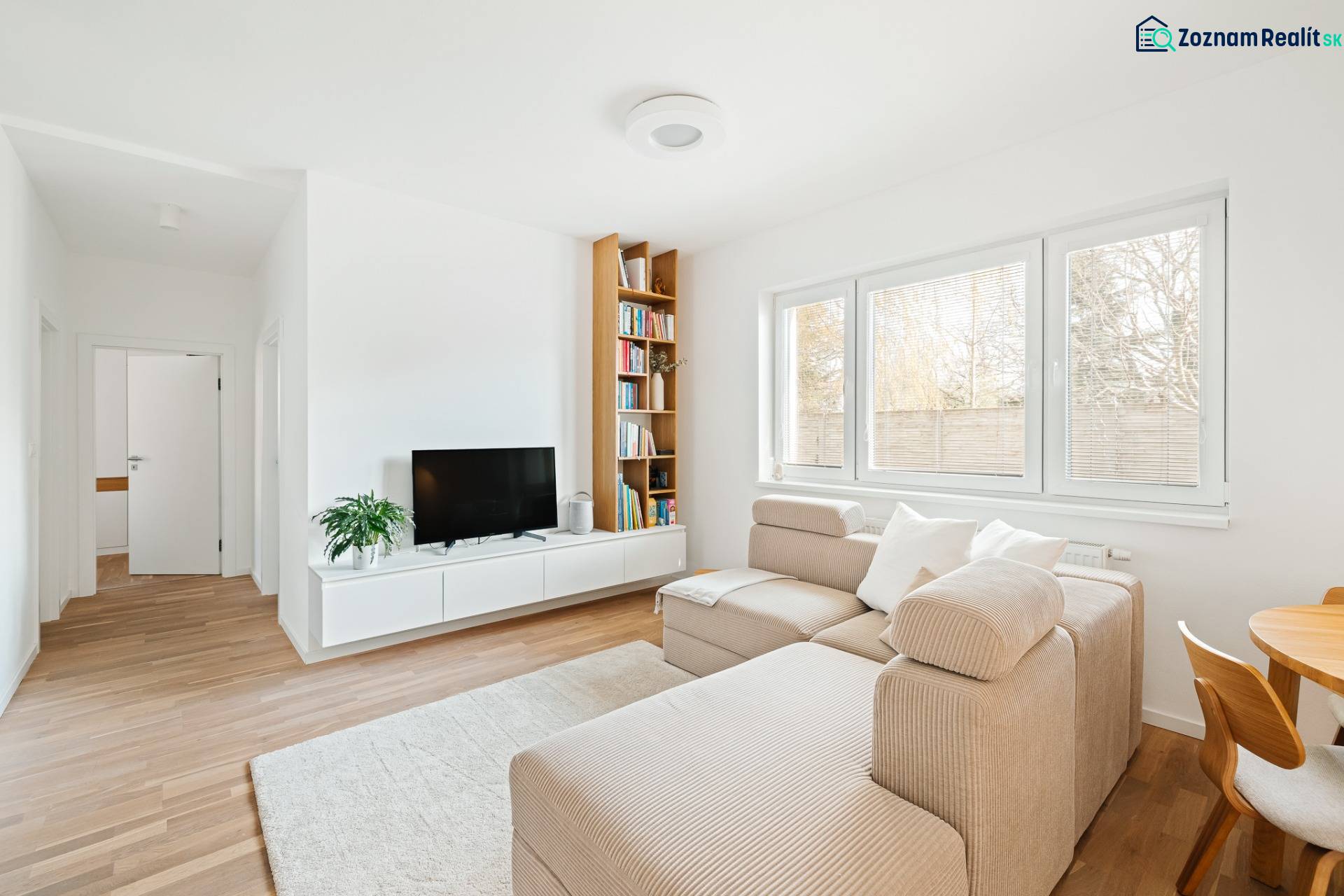 NUERA | PREDAJ 4i byt s predzáhradkou pri lese + 2x parking , BAIV - Svetlá obývačka v 4-izbovom byte s podlahou s dreveným dekorom, pohovkou a TV.