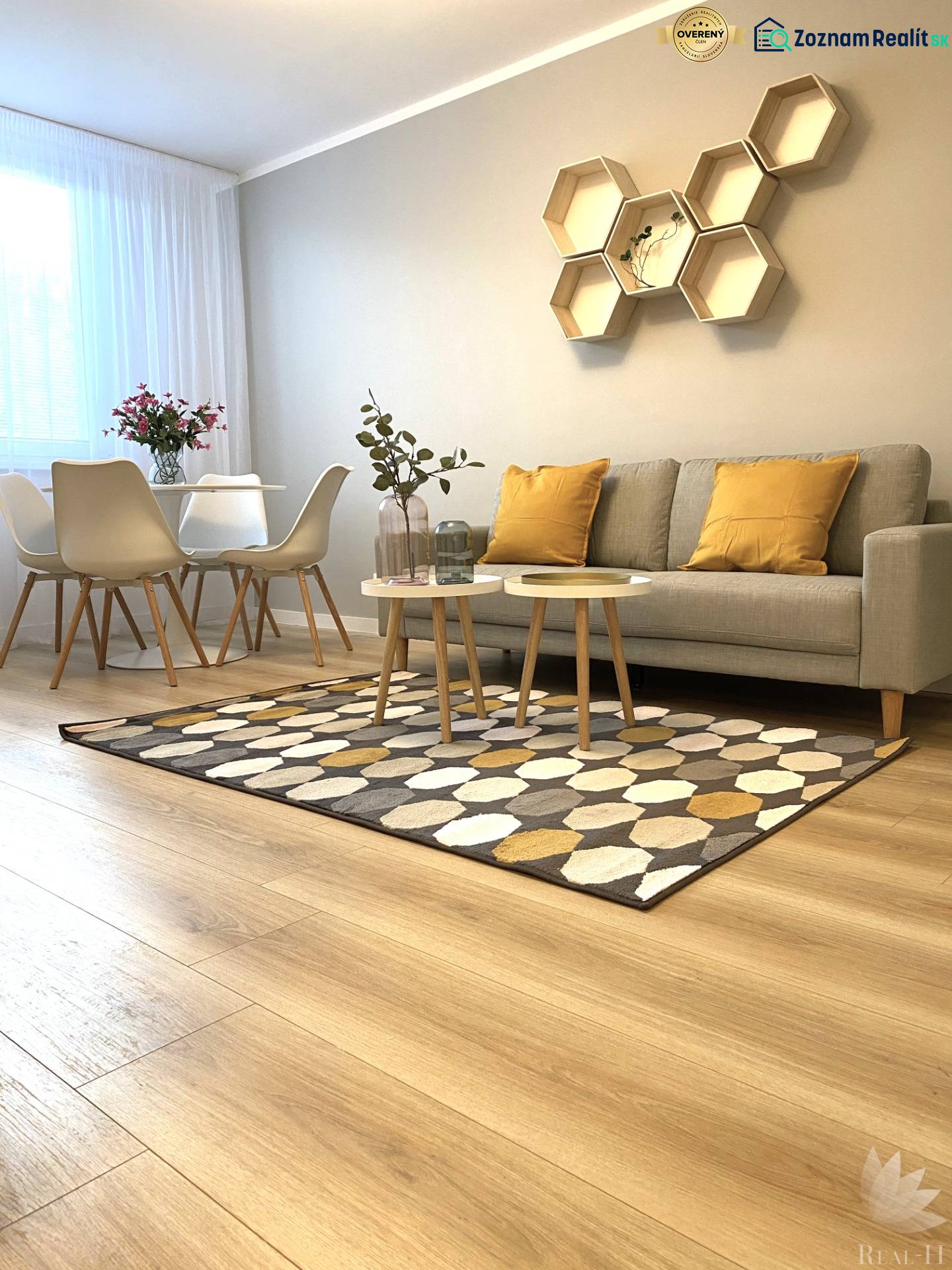 Dizajnový moderný 2 izbový byt Jurigovo nám. Bratislava IV Karlova Ves - 2-izbový byt s podlahou s dreveným dekorom, pohovkou, jedálenským stolom a geometrickými poličkami.