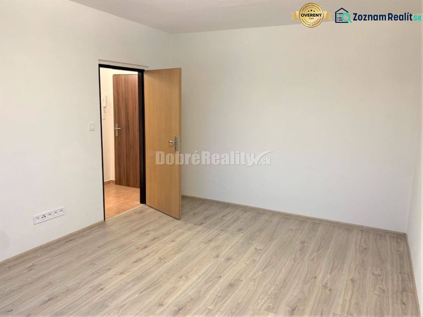 Nový nájomné 1 izbové byty v Prievidzi - ihneď k dispozícii - Izba v 1-izbovom byte s bielymi stenami a podlahou s dreveným dekorom.