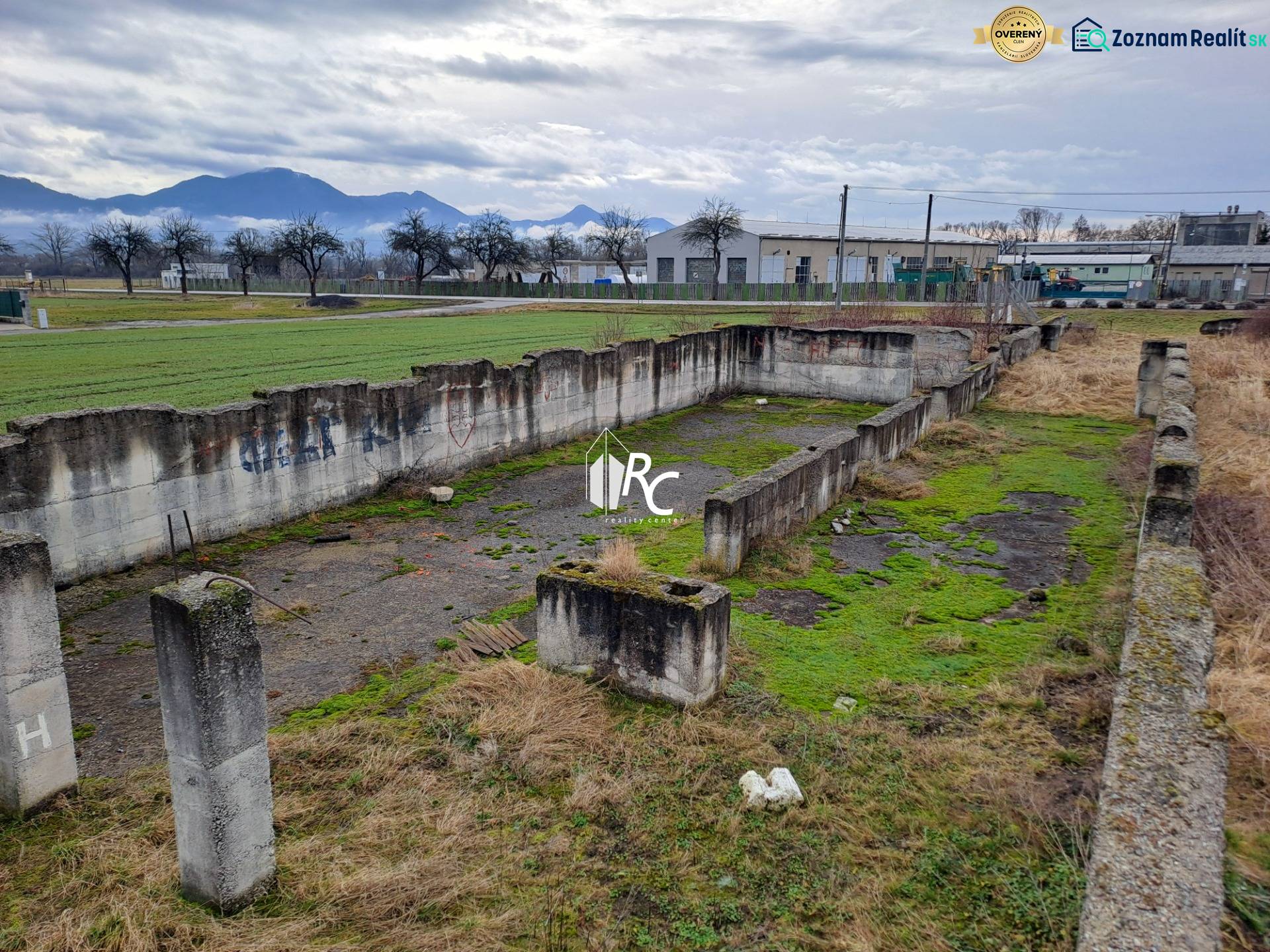 Stavebný pozemok 2 375 m² v obci Valča  - Opustené betónové základy na pozemkoch na bývanie v obci Valča s výhľadom na kopce.