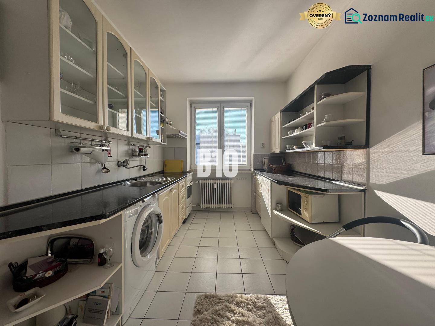 Sad na Studničkách - 2 izbový byt 60m2 - Kuchyňa v 2-izbovom byte s bielymi skrinkami a čiernou pracovnou doskou.