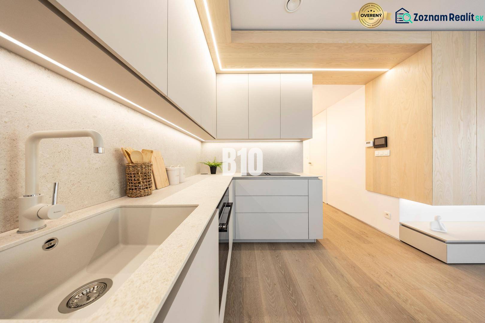LUXUSNÝ 3-IZBOVÝ BYT NA MIERU V NADČASOVEJ NOVOSTAVBE NA ZAČIATKU KOLI - Kuchyňa v 3-izbovom byte s podlahou s dreveným dekorom a minimalistickým dizajnom.