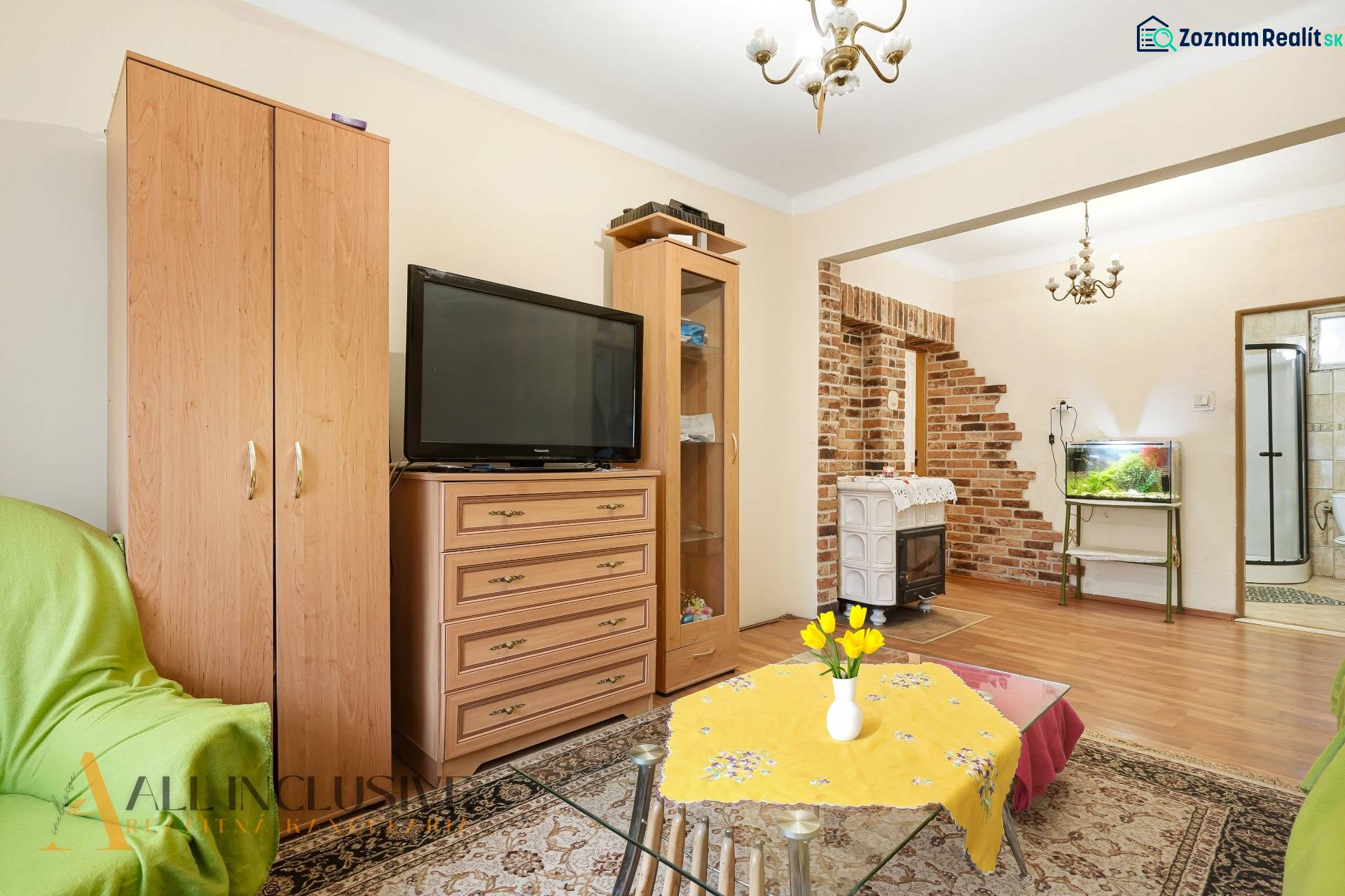 Na predaj 4-izb. rodinný dom s garážou, Okoč - Obývacia izba v rodinnom dome s tehlovými detailmi a podlahou s dreveným dekorom.