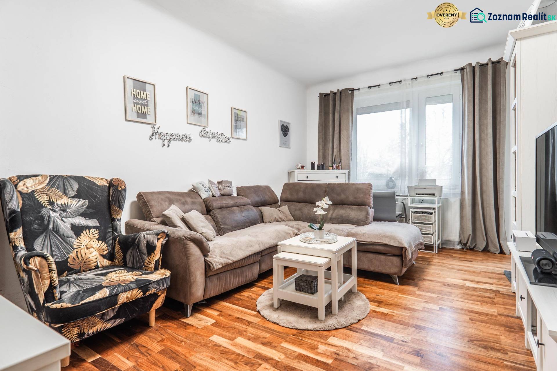 I Na predaj 2-i byt s terasou v Auersthal (Rakúsko) - Svetlá obývačka v 2-izbovom byte s pohovkou, kreslom a podlahou s dreveným dekorom.