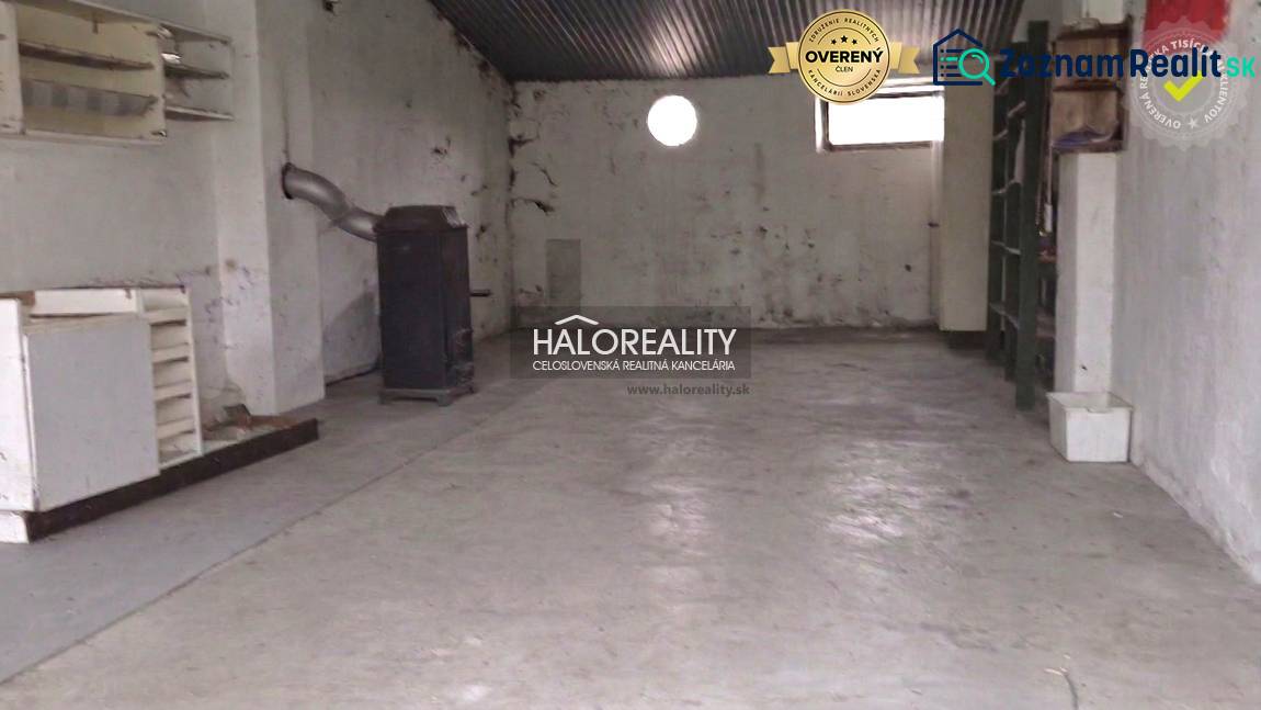 Predaj, chalupa Poltár - EXKLUZÍVNE HALO REALITY - Priestor v chate s jednoduchým kachľovým sporákom a oknami.