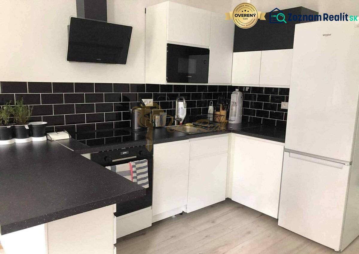 1,5 izb. byt s predzáhradkou, Podunajské Biskupice, projekt Oppidum - Biela kuchyňa s čiernymi obkladmi a podlahou s dreveným dekorom v 2-izbovom byte.