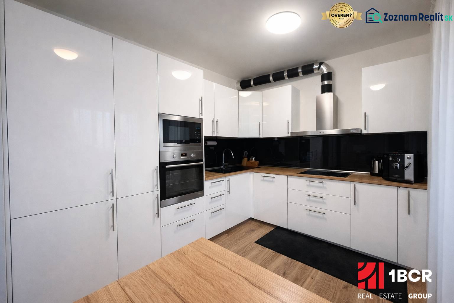 EXKLUZÍVNY 3-IZBOVÝ BYT V SÚKROMNOM KOMPLEXE |2x PARKING | NA PIESKU,  - Kuchyňa v 3-izbovom byte s bielymi skrinkami a podlahou s dreveným dekorom.
